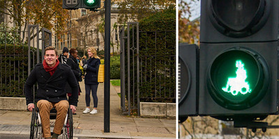 Photo of a man in a wheelchair using a pedestrian crossing with the new green wheelchair lights